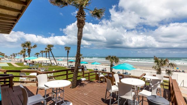A beachside deck with tables and chairs overlooking the ocean.