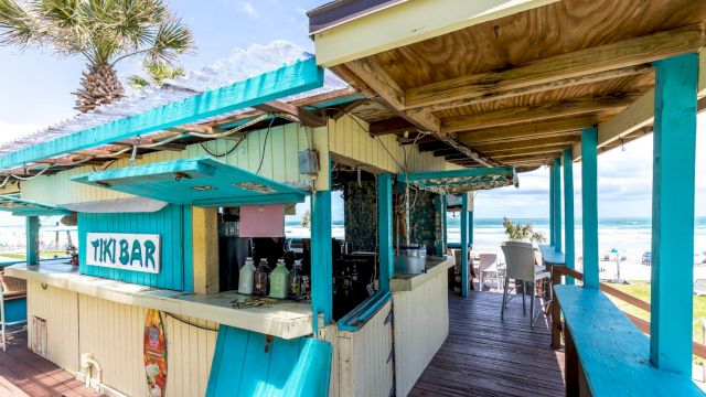 A beachside tiki bar with an outdoor counter and seating area