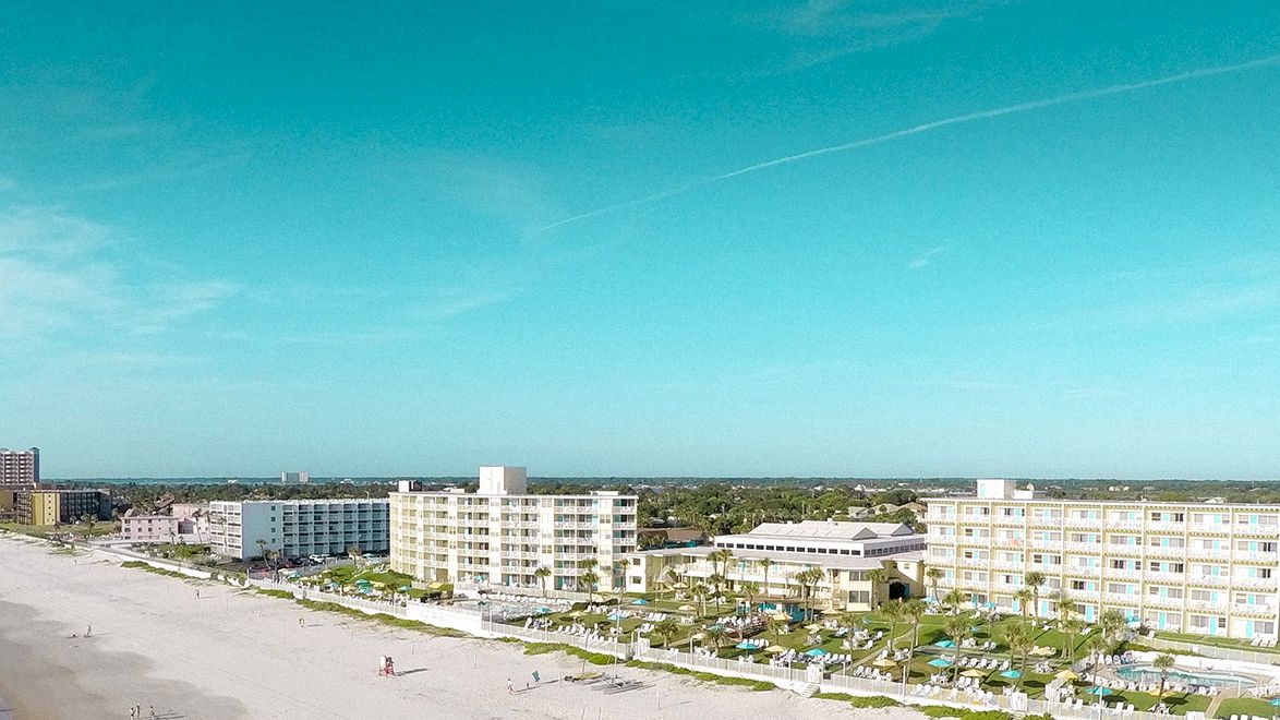 The image shows a coastal city with buildings lining the beach, a wide shoreline, and a clear blue sky, ending the sentence.