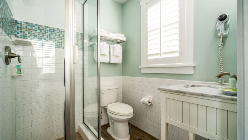 A clean bathroom with a shower, toilet, sink, and window.