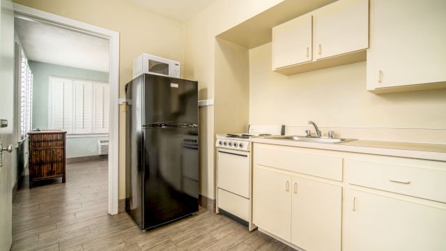 A kitchenette with white cabinets, a sink, and appliances including a black refrigerator and a white microwave.