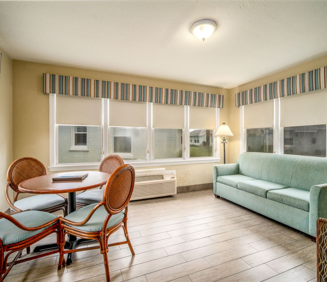 A furnished living room with a sofa, dining table, and chairs.