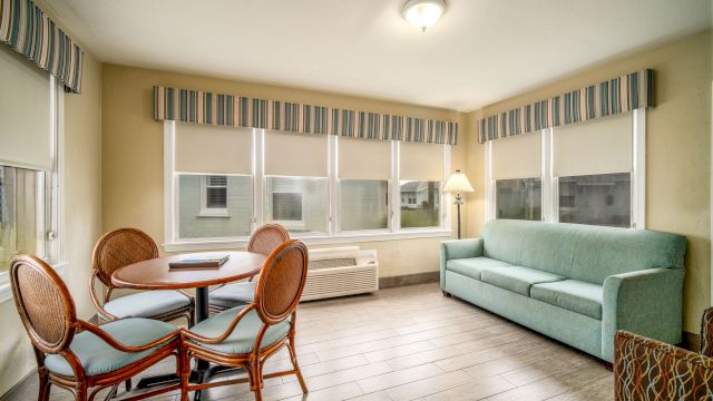 A wide view of a living area with a sofa, dining table, and windows.
