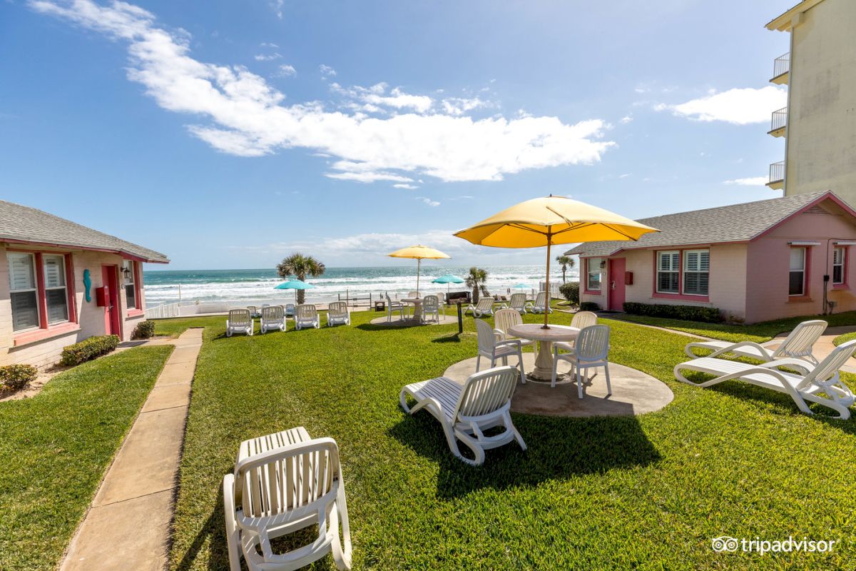 A grassy area with white furniture and yellow umbrellas, overlooking the beach and ocean.