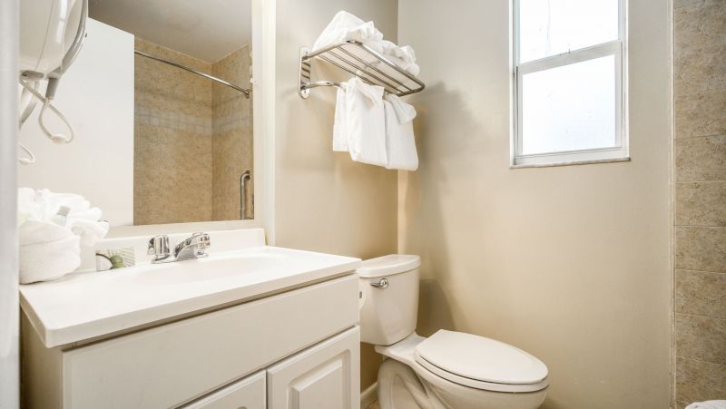 A clean bathroom with a toilet, sink, mirror, and towels.