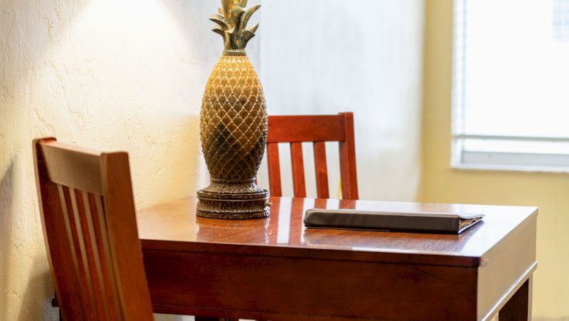 a wooden table with two chairs and a pineapple statue