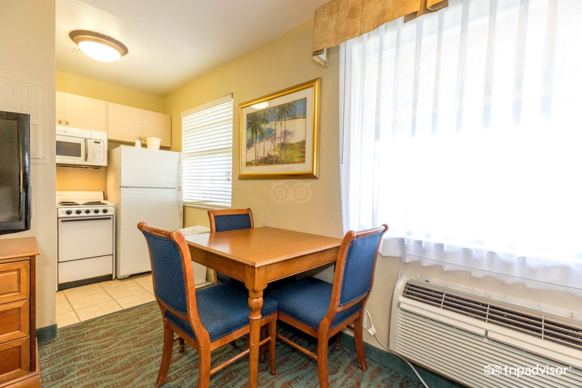 A kitchenette with a dining table, refrigerator, stove, and microwave.