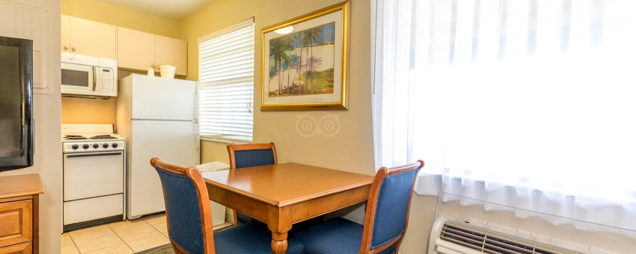 A kitchenette with a dining table, refrigerator, stove, and microwave.