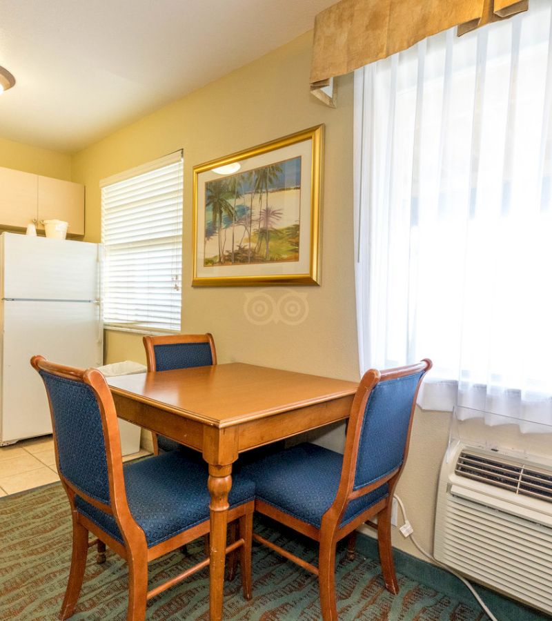 A small kitchenette with a table, chairs, refrigerator, and window.