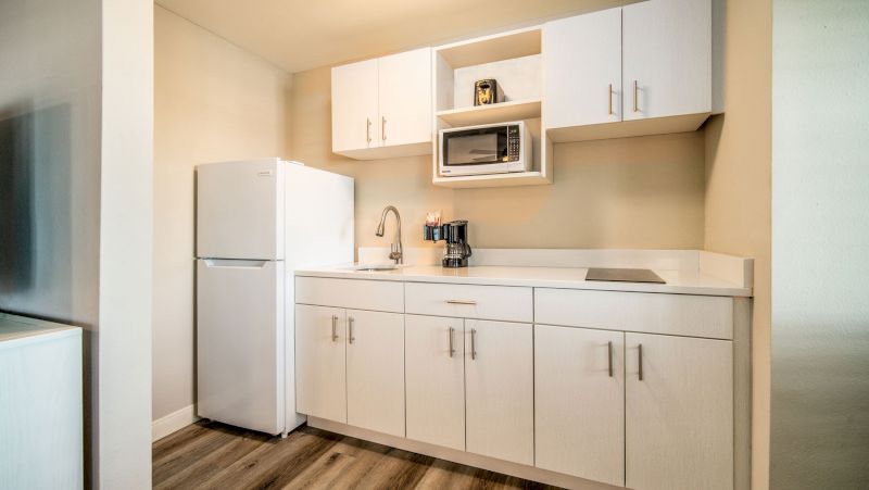 A compact kitchenette with white cabinets and appliances.