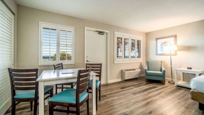 A wide view of a hotel room with a dining area, a bed, and a sitting area.