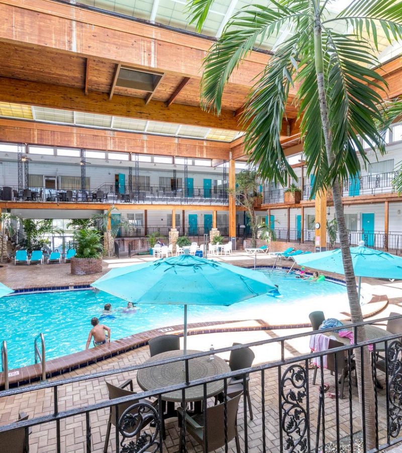 A large indoor pool with people swimming and lounging around it.