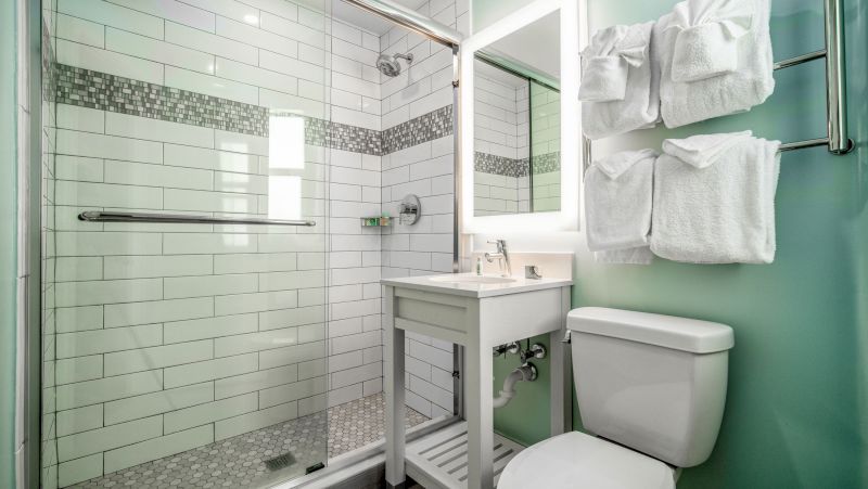 A bathroom with a tiled shower, toilet, sink, and towels.