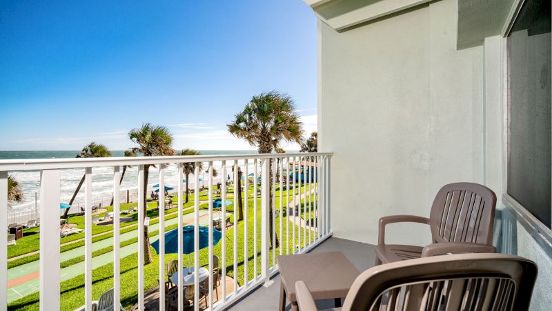 A balcony with two chairs and a table overlooking the ocean.