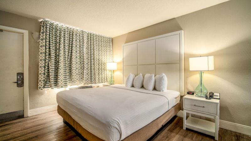 A hotel room with a large bed, two nightstands with lamps, and a window with curtains.
