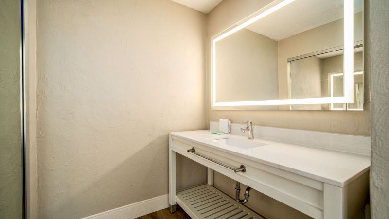 A clean bathroom sink area with a large mirror and white countertop