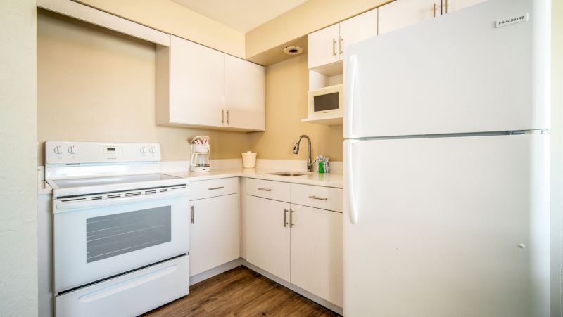 A compact kitchenette with white appliances and cabinets