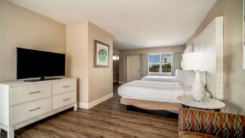 A hotel room with two beds, a dresser, and a TV