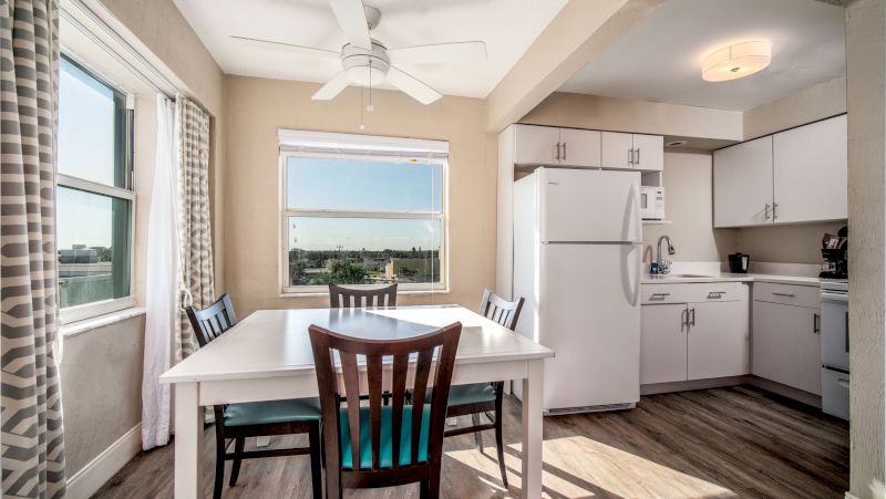 A bright kitchen and dining area with white appliances and a large window.