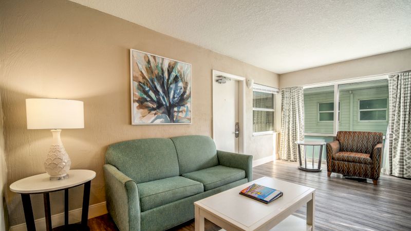 A wide view of a living room with a green sofa, a white coffee table, and a brown armchair.