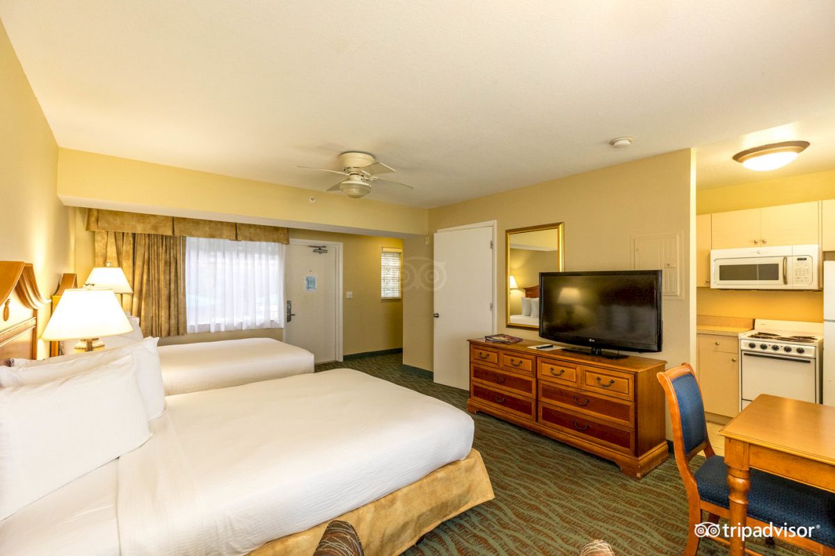 A hotel room with two beds, a kitchenette, and a TV