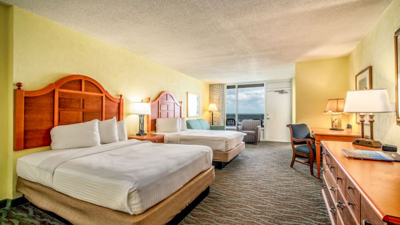 A hotel room with two double beds, a desk, and a chair.