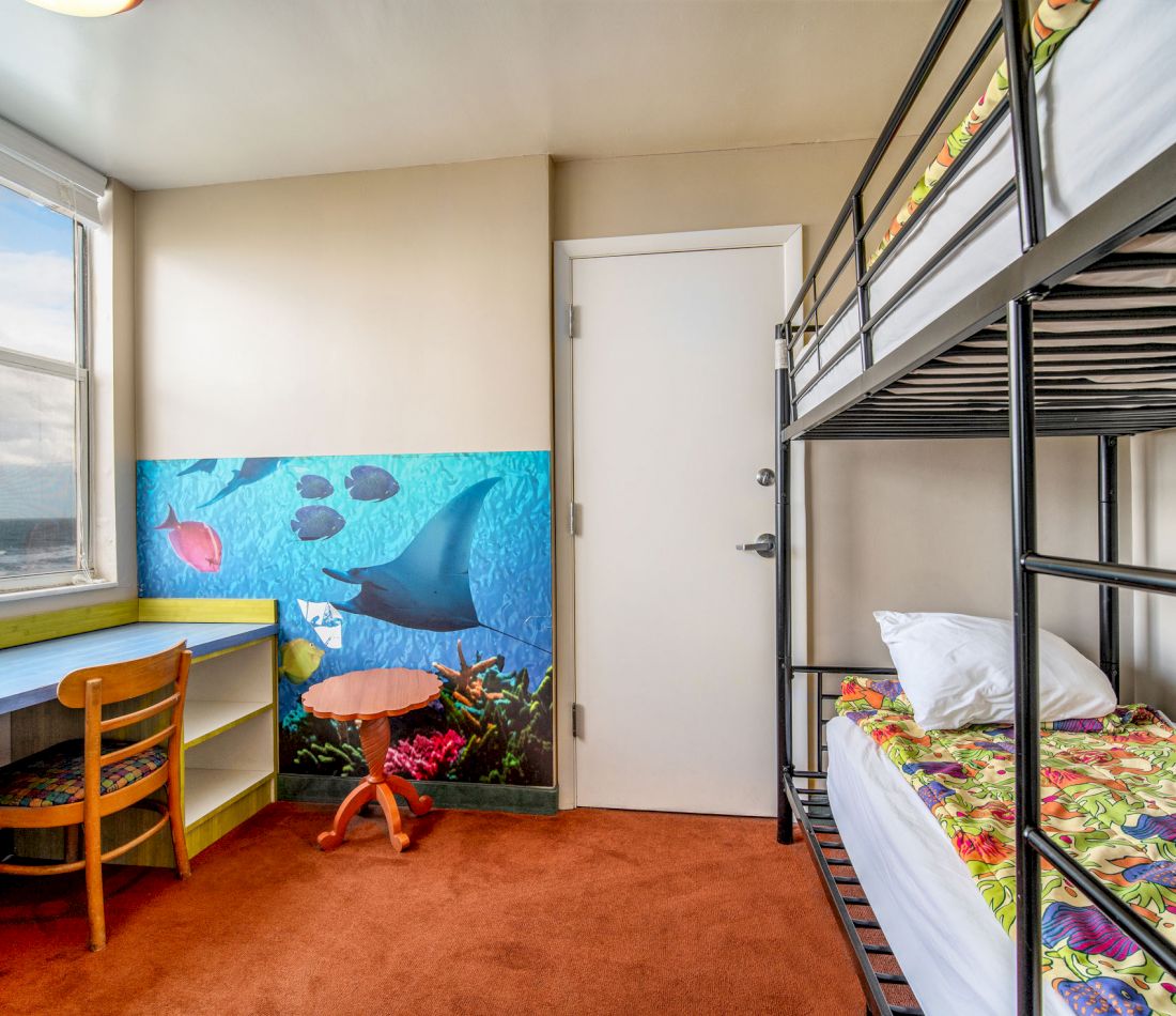 A family room with bunk beds, a desk, and an ocean-themed mural.
