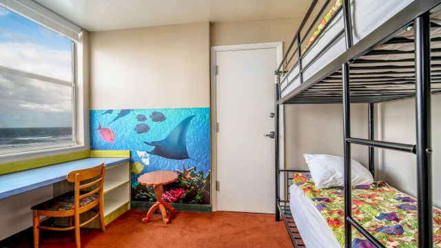 A compact guest room with bunk beds, a desk, and an ocean view.