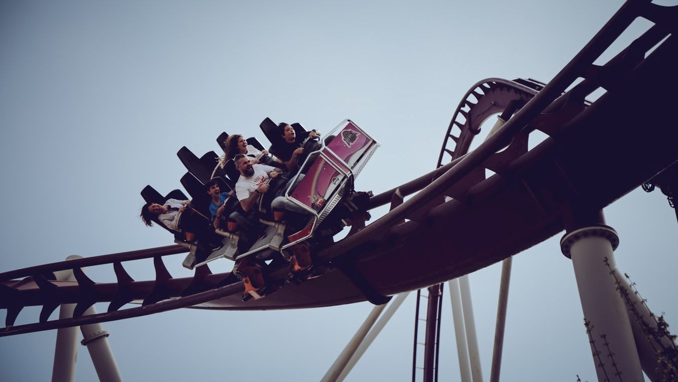 The image shows people riding a roller coaster on a curved track against a cloudy sky, appearing to enjoy the thrill of the ride, ending the sentence.