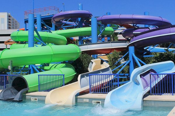 The image shows a colorful water park with multiple curved slides, each in different colors, ending in a pool.