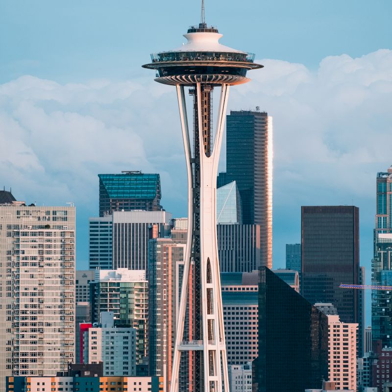 This image shows the Space Needle, a famous observation tower in Seattle, with a backdrop of the city's skyline and various high-rise buildings.