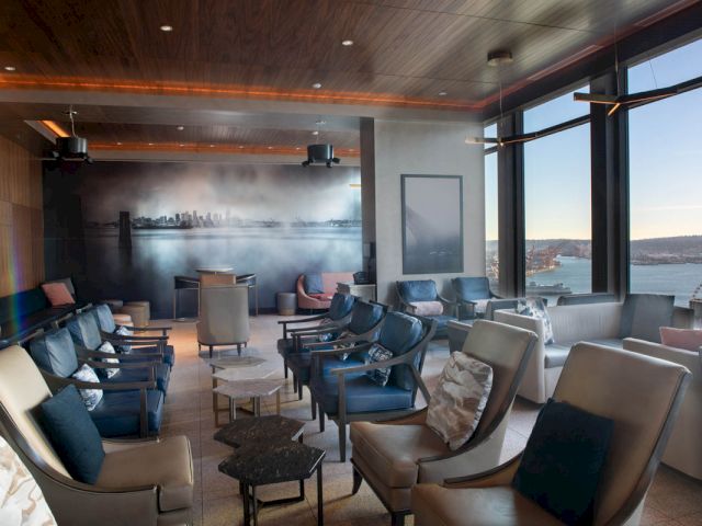 A stylish lounge with comfortable seating, large windows, and a city view.